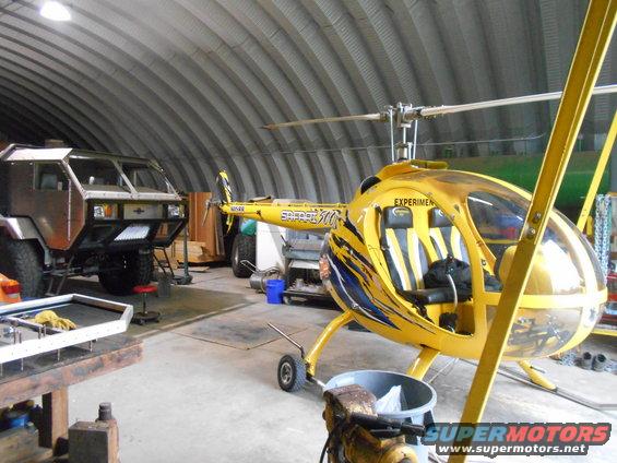 Yellow helicopter and custom truck inside a large garage