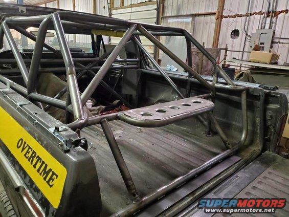Truck bed with custom roll cage, yellow 'OVERTIME' sticker, and metal bracing