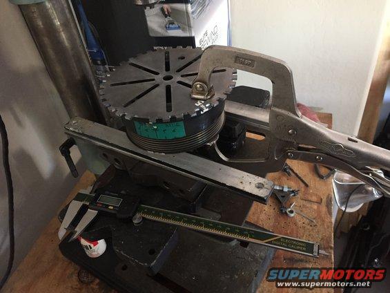 Rotary table clamped to a machine with digital calipers and a ruler nearby