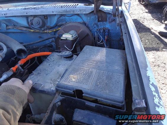 1994 Ford Bronco engine bay with fuse box open, showing wiring and fluid reservoir