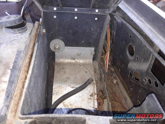 Empty battery tray with some wires and a hose visible