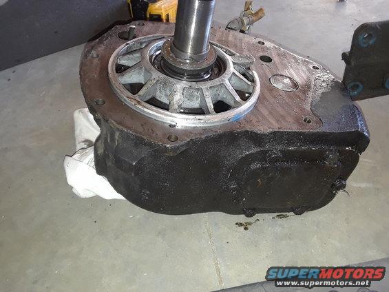 Black automotive transmission housing with a silver metal component and shaft, resting on a white cloth