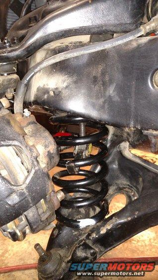 Black coil spring and brake caliper on car suspension