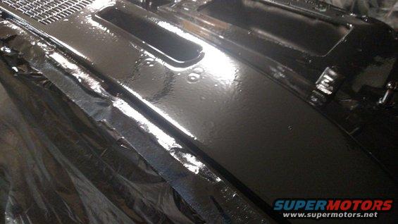 Black painted car dashboard section with a grate and some indentations. Supermotors.net logo visible
