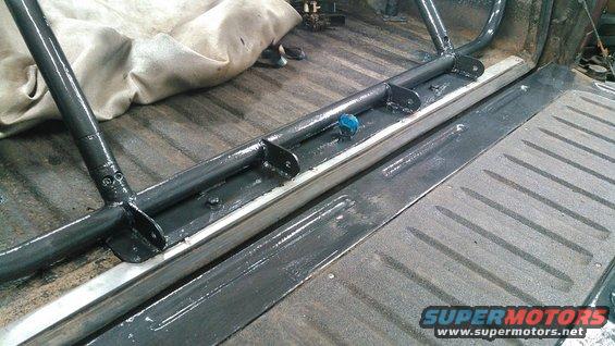 Roll cage installed in truck bed, showing mounting brackets and tubing