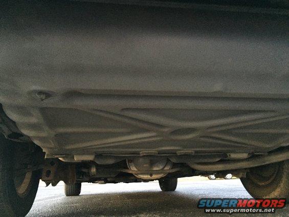 Underside view of a car, showing the fuel tank and rear differential. Tires visible