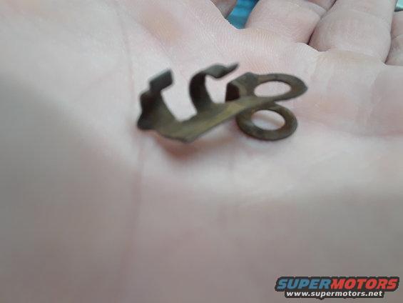 Rusty metal clip with two loops, held in a person's palm
