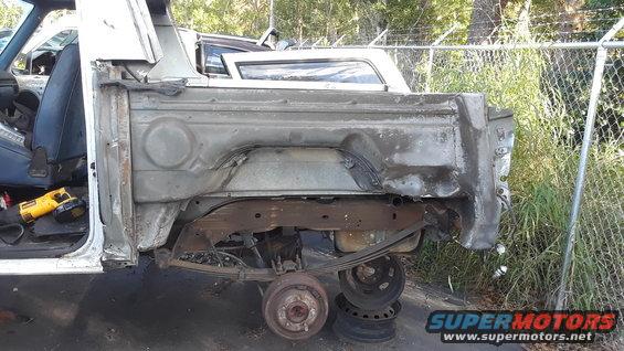Rear quarter panel of a damaged pickup truck with exposed frame and suspension