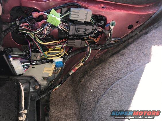 Vehicle wiring harness with many colorful wires and connectors, some taped