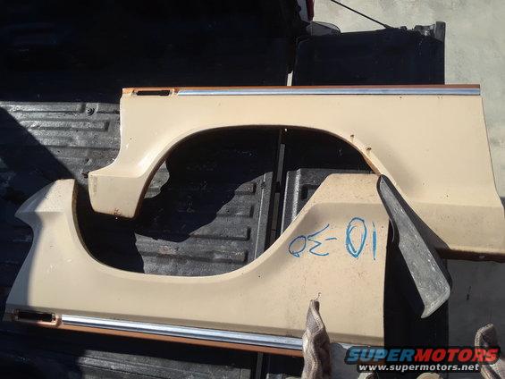Tan vehicle fender sections with chrome trim and blue writing on one part