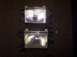 1988 Ford Bronco - A pair of vehicle headlight assemblies are displayed on a dark, textured surface.