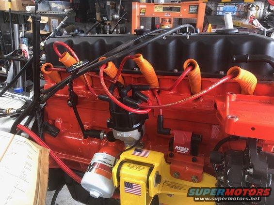 Close-up of an engine block with red paint, orange spark plug wire boots, a distributor, and an MSD ignition box. A K&N oil filter is also visible