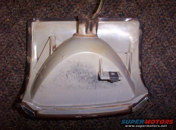 Back of a white turn signal housing with chrome trim and wires