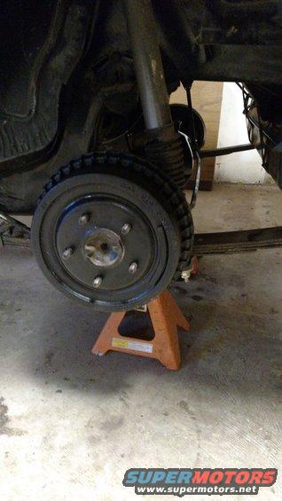 Rear drum brake assembly on an orange jack stand, showing suspension and leaf spring