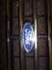 1988 Ford Bronco - The blue Ford emblem is centered on a chrome grille with vertical bars.