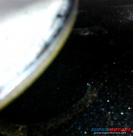 Close-up of a tire and wheel well, showing dark, textured ground