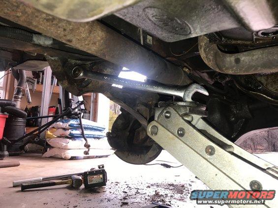 wrench on suspension part, jack holding up axle