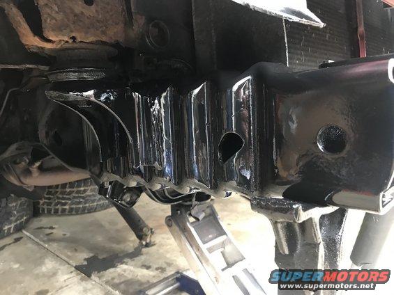 Close-up of black-painted vehicle frame rails and suspension components on jack stands