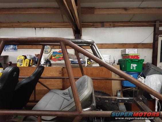 Interior of a custom off-road vehicle with roll cage and two seats. Visible text: SUPERMOTORS