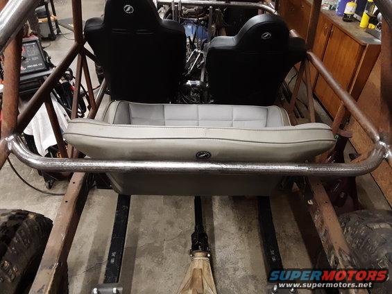 Buggy interior with two bucket seats and a bench seat, roll cage, and exposed frame