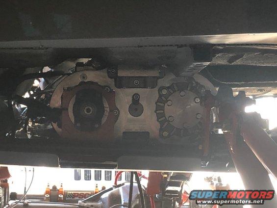 Underside view of a vehicle's transfer case and drivetrain components, with some orange accents