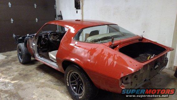 Red 1979 Chevrolet Camaro with doors and trunk open, in a garage. Front fenders and hood are missing