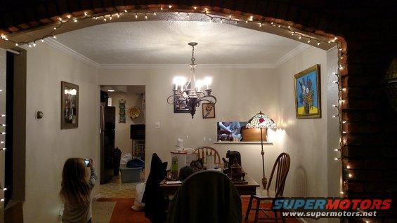 Interior of a dining room with a girl taking a photo, a chandelier, and string lights