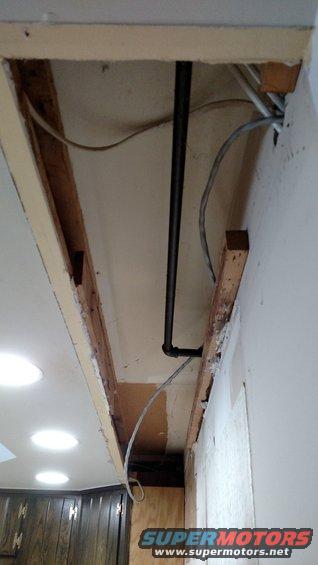 exposed ceiling joists with black pipe and electrical wires, part of a kitchen remodel