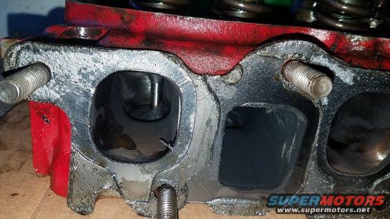 Close-up of a red engine cylinder head with intake and exhaust ports