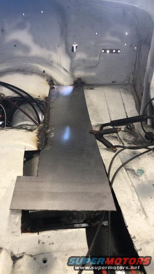 Welding a metal patch onto the floor of a vehicle, likely for rust repair