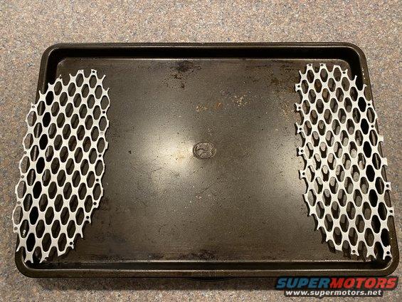 Two silver honeycomb grilles on a dark baking sheet