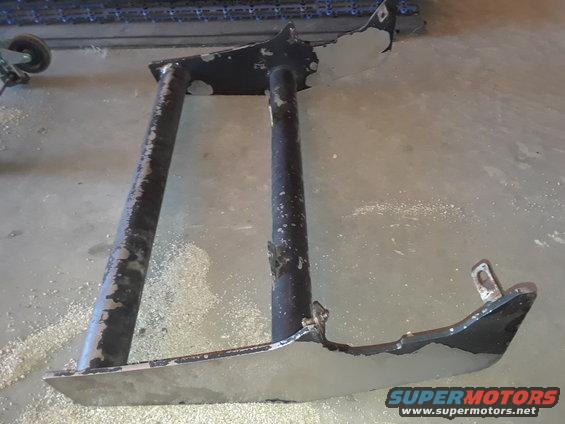 Black metal frame part with chipped paint, on a concrete floor
