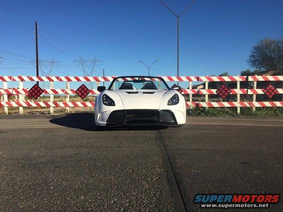 White convertible sports car parked in front of a red and white striped barrier