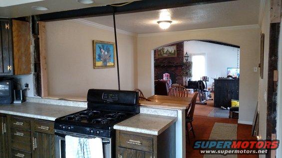 Kitchen area with a stove and counter, opening to a dining and living area with a fireplace