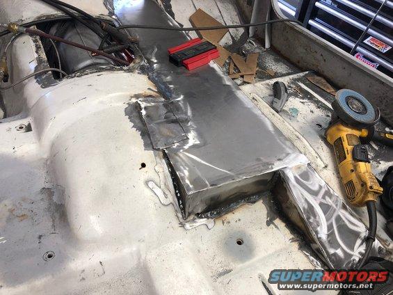 Vehicle interior floor with metal patches and welding, angle grinder visible
