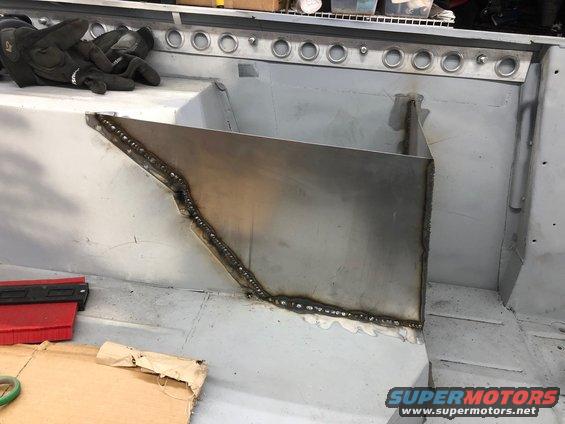 Interior of a vehicle undergoing body work, showing freshly welded metal panels and a pair of work gloves