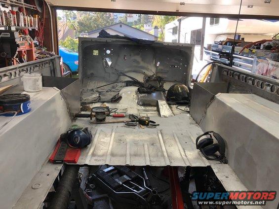 Jeep CJ-7 interior, stripped down for bodywork, showing metal floor and sides, with tools scattered