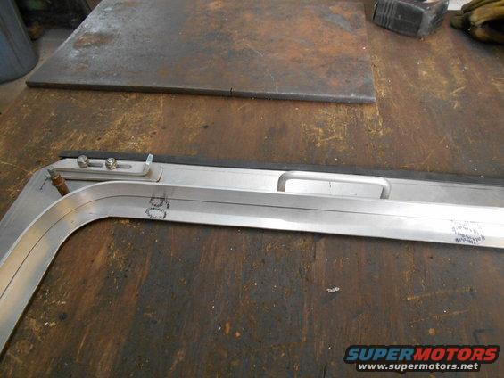 Metal frame with a handle, screws, and markings on a workbench