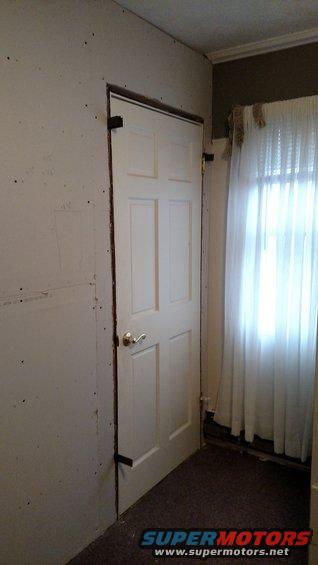 Interior doorway with a white six-panel door, a window with sheer curtains, and a watermark for Supermotors.net