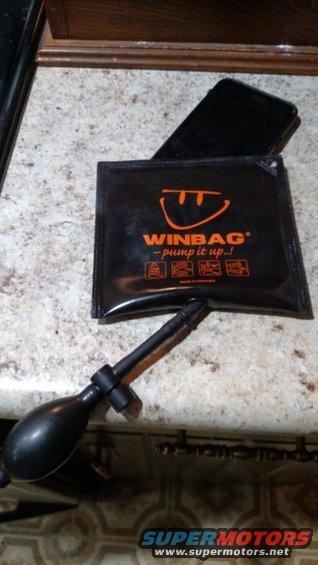 Black WINBAG with orange logo and pump next to a black smartphone on a speckled countertop