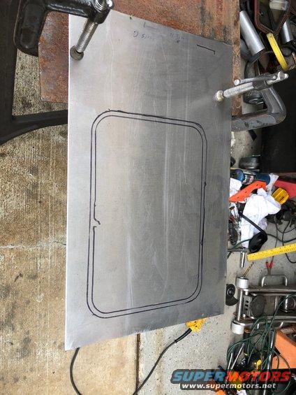 Sheet metal with a template for a cut-out, clamped to a workbench