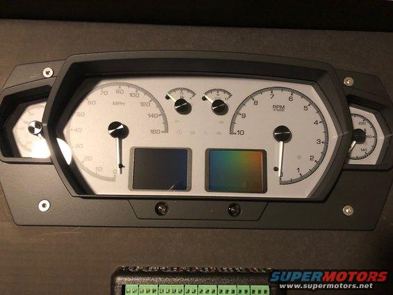 Aftermarket digital gauge cluster with MPH and RPM gauges, two small screens, and side gauges