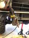 1981 Ford Bronco - A person is shown welding a bracket onto the front frame of a vehicle, supported by jack stands.