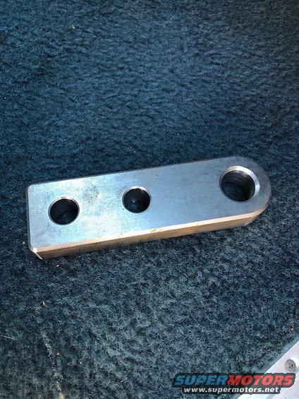 Metal bracket with two small holes and one larger threaded hole