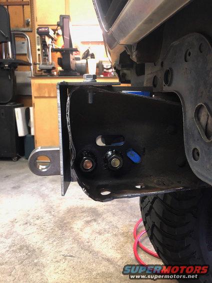 Vehicle frame with tow hitch attachment, showing bolts and metal brackets. Tire visible below
