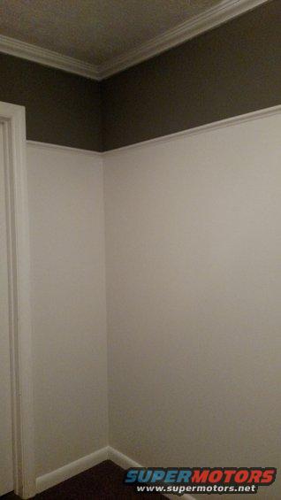 Interior corner of a room with white walls, dark ceiling, and a door frame. Supermotors.net logo visible