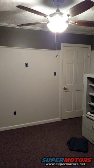 Room with ceiling fan, white door, and carpet. Electrical boxes are visible on the wall