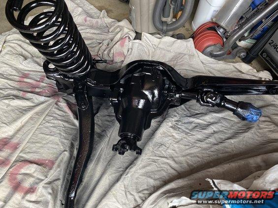 Black front axle assembly with coil spring, part of a vehicle rebuild