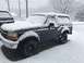 2008 Ford Focus - A Ford Bronco is parked outside during a snowstorm, with snow covering its body and the surrounding area.