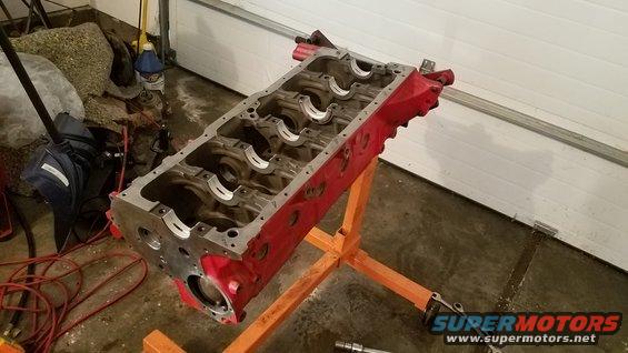 Red engine block on an orange engine stand in a garage